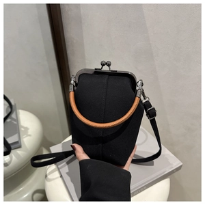 Details der schwarzen Segeltuchtasche mit braunem Webgriff und Vintage-Bügelverschluss