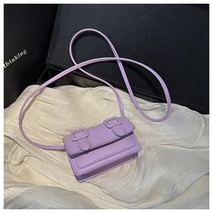 Detail view of mini lavender PU leather crossbody bag on soft white fabric background