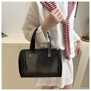 Detail of black mesh cylinder bag featuring golden zipper and premium leather handles