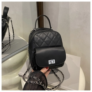 Detail of black quilted mini backpack with silver metal twist lock and chain strap