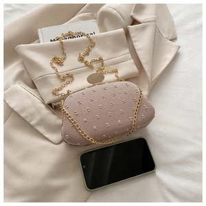 Detail of elegant pink crossbody bag with gold chain strap and crystal-encrusted oval clasp