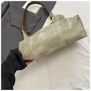 Detail of light green canvas tote bag with brown leather strap and textured fabric