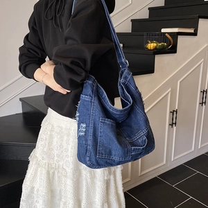 Blue denim tote bag with vintage frayed edges and multiple pockets in a spacious design