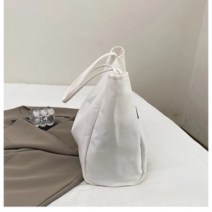 Detail shot of a white canvas tote bag showing thick texture and large side structure
