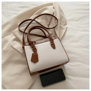 Close-up of brown and white contrast leather handbag on a beige suit in professional style