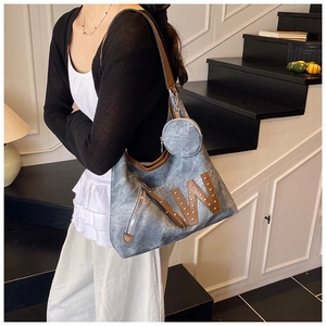 Detail of grey canvas tote bag with brown leather W-letter decor and side zipper