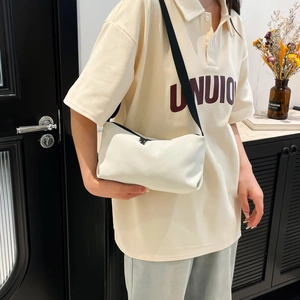 Sac fourre-tout crème minimaliste avec bandoulière noire réglable porté par un mannequin