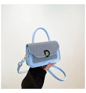 Detail of light blue handbag with striped flap and bold D-shaped metallic buckle