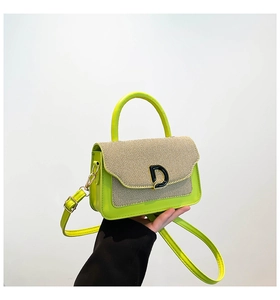 Detail of neon green leather bag with woven contrast flap and black D-shaped buckle