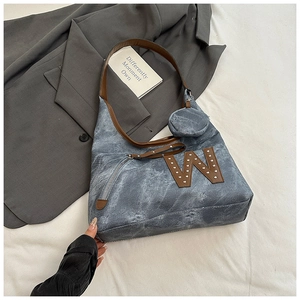 Close-up of denim tote bag with leather W patch, metal rivets and matching mini coin purse