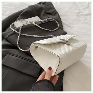 Detail of white quilted crossbody bag with metal chain strap and sleek buckle closure