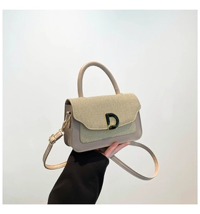 Detail of beige tote bag featuring straw texture flap and iconic black D metal buckle
