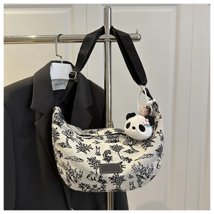 Detail of crescent canvas tote with rabbit print and panda plush charm on a hanger
