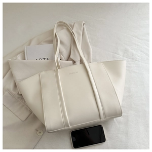 Detail of minimalist cream tote bag showing FASHION embossing and smartphone for scale