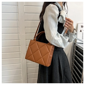 Brown quilted crossbody bag styled with a light blue ruffled shirt for a casual look