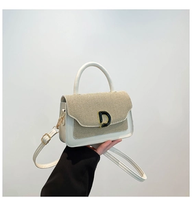 Detail of beige textured fabric and white leather handbag with a metal D-shaped buckle