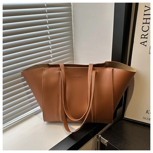 Detail of a large brown leather tote bag showing the debossed FASHION text and soft texture