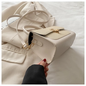 Detail of beige square bag featuring woven texture flap and golden metallic twist lock