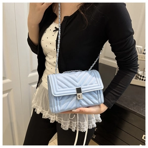 Close-up of light blue quilted leather bag featuring a silver chain and metal lock detail