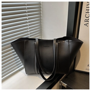 Detail of black leather tote bag with embossed fashion text and long shoulder straps