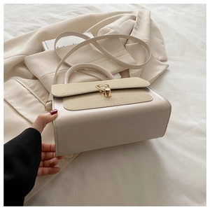Close-up of cream leather handbag with woven texture flap and golden hardware