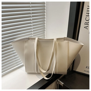 Detail of cream-colored leather tote bag with FASHION logo and flexible texture