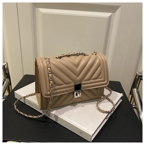 Close-up of beige quilted crossbody bag with V-pattern stitching and silver chain strap