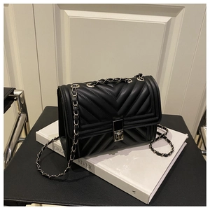 Close-up of black quilted leather crossbody bag with silver V-stitch and metal push-lock