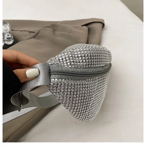 Macro shot of silver rhinestone crossbody bag featuring a wide nylon strap and metal buckle