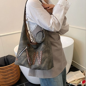Chic grey-green canvas tote bag with brown leather trim and rivet W detail on model