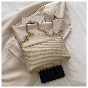 Détail d'un sac enveloppe tissé beige clair avec bandoulière chaîne dorée élégant