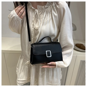 Détail d'un petit sac carré noir minimaliste avec boucle argentée porté par une femme