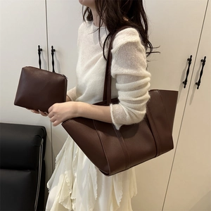 Minimalist dark brown leather tote bag with matching zippered pouch shown in a home setting