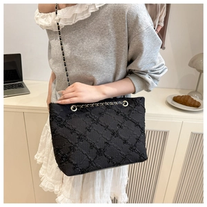 Close-up of black quilted tote bag with chain strap and shimmer texture details