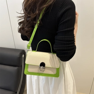 Green leather and cream canvas crossbody bag with silver buckle worn by a model