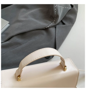 Gros plan du sac à main crème avec ferrures dorées et détails de couture de qualité