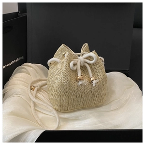 Detail of straw bucket bag featuring drawstring tassels and premium gift box packaging