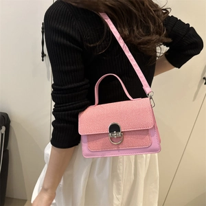 Pink textured crossbody bag with metal ring buckle shown on model in a stylish setting
