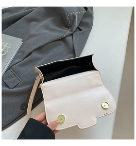 Détail de l'intérieur du sac beige en PU avec boucles magnétiques dorées sur une veste