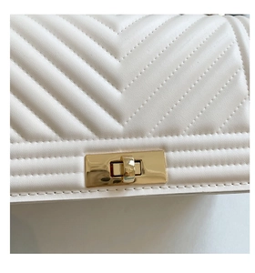 Detail of white chevron quilted leather bag with elegant light gold metal twist lock