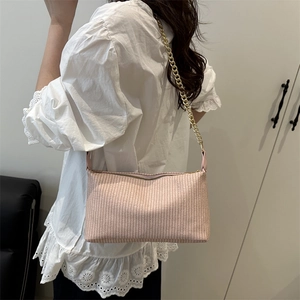Sac à bandoulière tissé élégant en abricot avec chaîne dorée porté par un mannequin