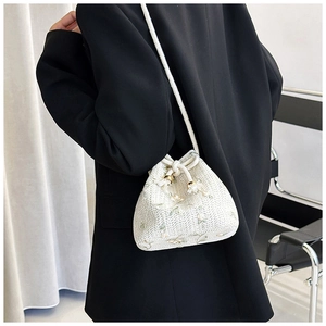 Detail of white woven bucket bag with floral embroidery and adjustable crossbody strap