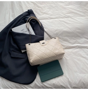 Detail of quilted stitching and metal twist lock on the cream chain tote bag