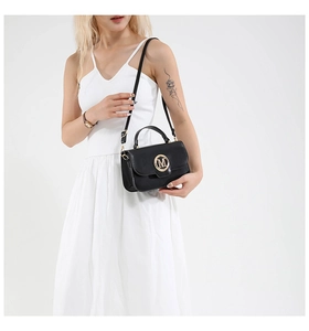 Detail of black leather crossbody bag featuring gold M logo and adjustable strap