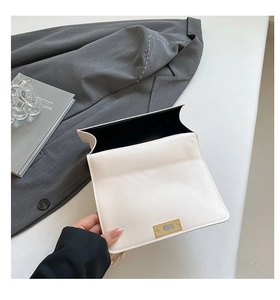 Detail view of the white leather bag interior with gold clasp and black lining