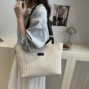Minimalist beige straw tote bag with black leather straps and fashion logo patch