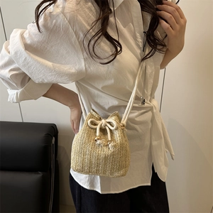 Handwoven straw bucket bag with drawstring closure and white rope strap on female model