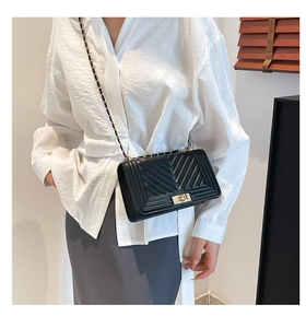 Detail of black quilted shoulder bag featuring V-shaped stitching and gold metal lock clasp