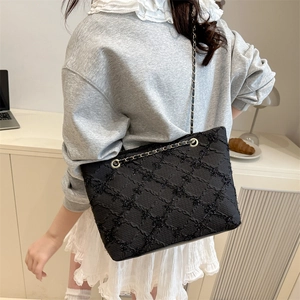 Chic black quilted tote bag with gold chain strap worn by model in elegant office setting