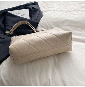 Detail of beige quilted tote bag with soft leather texture and chain strap on bed